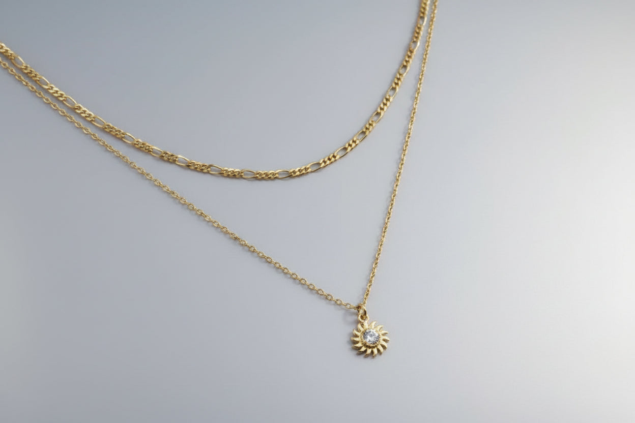 Gold chain necklace with a sun pendant on a red background